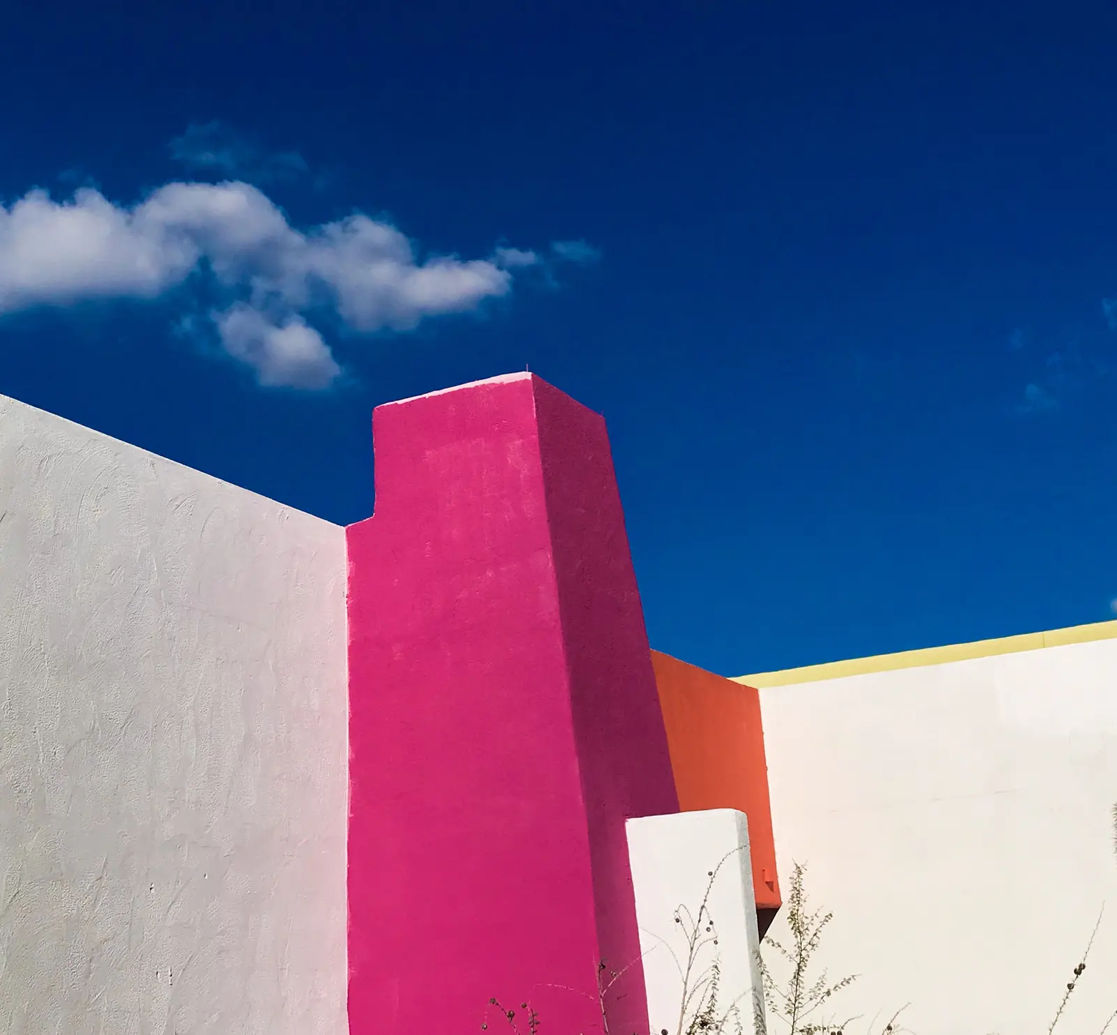 A magenta and white building facade against a deep blue sky