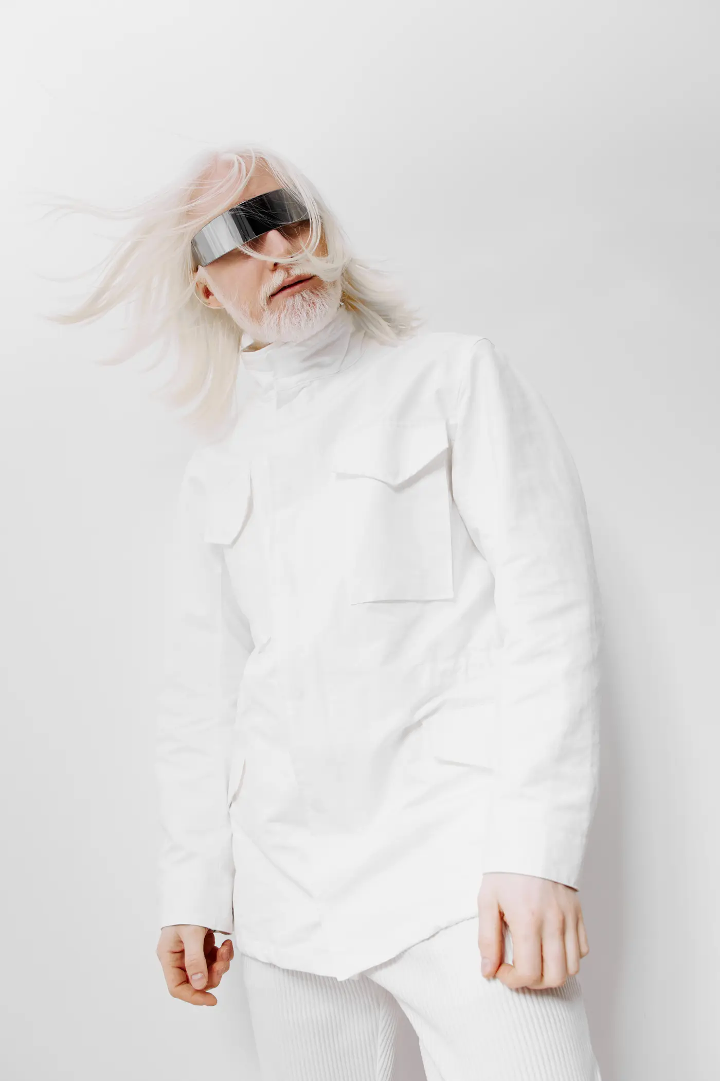 A person with long white hair in a white jacket and mirrored visor